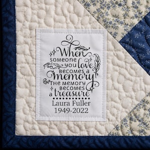 May include: A quilted square with a white label featuring the text "When someone you love becomes a memory, the memory becomes a treasure." The label also includes the name "Laura Fuller 1949-2022." The quilt has a blue floral pattern.