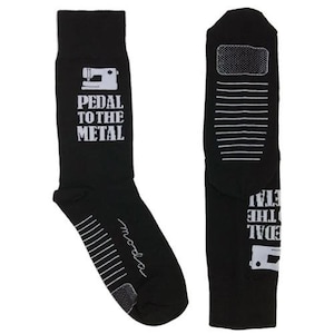 May include: Black socks with white text that reads "Pedal to the Metal" and a sewing machine graphic. The socks have a white stripe pattern on the back.