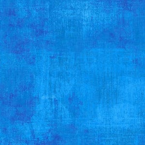 May include: A textured fabric with a blue color palette. The design features a blend of light and dark blues, creating a mottled effect. The fabric has a slightly distressed appearance, with visible brushstroke-like patterns.