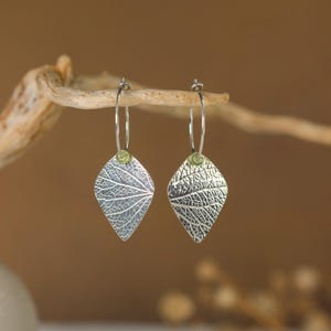 Mini oorringen met nerven van hortensiablaadjes. Oorbellen van 950 zilver. Lentegroene peridot edelsteen.