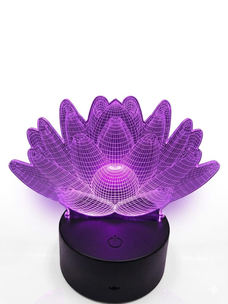 May include: A purple lotus flower-shaped LED lamp. The lamp has a 3D wireframe design and sits on a black base. The lamp is illuminated with a soft purple glow, creating a calming ambiance. The base has a power button.