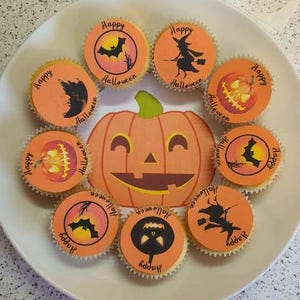 May include: A collection of nine orange and black Halloween cupcakes with various designs, including bats, pumpkins, and witches. The cupcakes are decorated with the words "Happy Halloween".