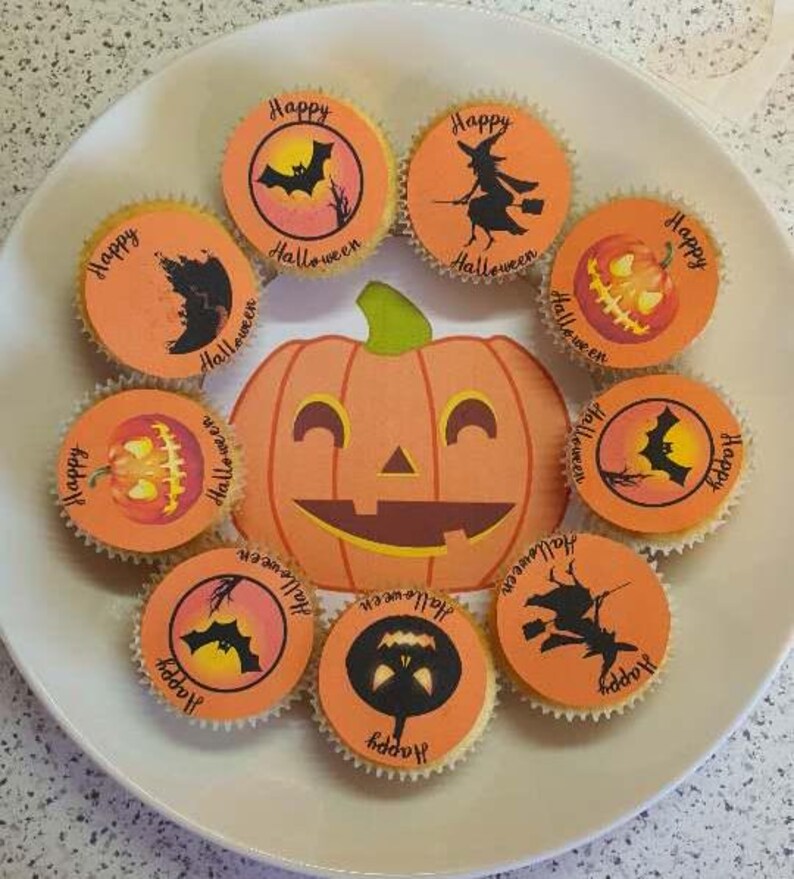 May include: A collection of nine orange and black Halloween cupcakes with various designs, including bats, pumpkins, and witches. The cupcakes are decorated with the words "Happy Halloween".