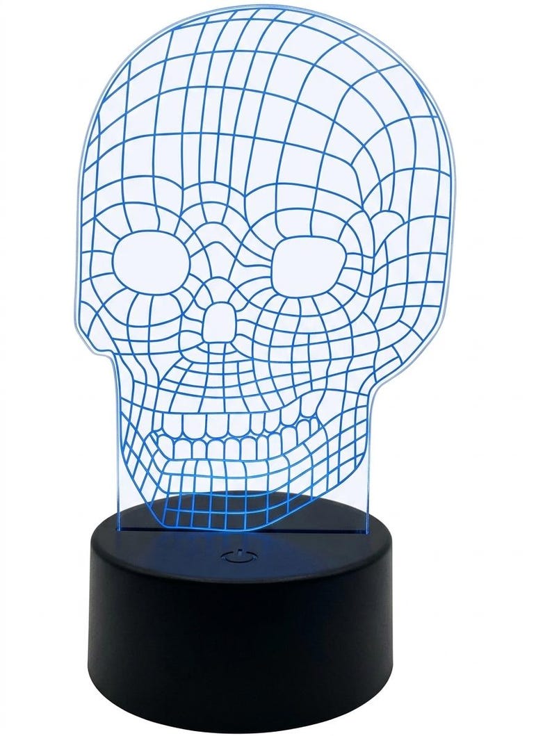 May include: A blue wireframe skull-shaped LED lamp. The skull design is a grid of blue lines, with eye and nose openings. The lamp sits on a black, cylindrical base that emits a soft blue glow.