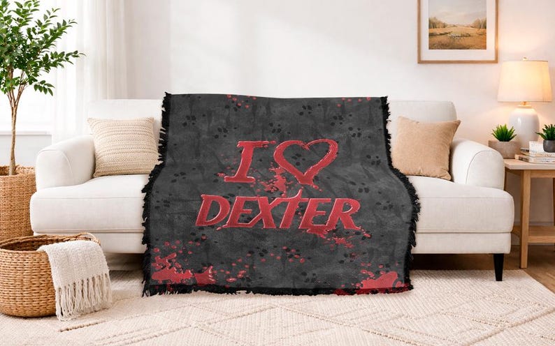 May include: A black throw blanket with the words "I ❤️ DEXTER" in red, displayed on a white couch. The blanket has a distressed design with red splatter accents and a fringed edge. The couch is in a living room setting.
