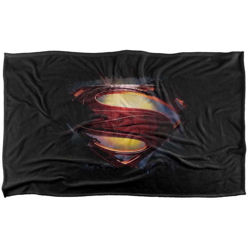 Puede incluir: Manta negra con el logotipo de Superman en rojo, amarillo y azul. El logotipo tiene un aspecto desgastado y usado. La manta es rectangular y est&aacute; hecha de un material suave.