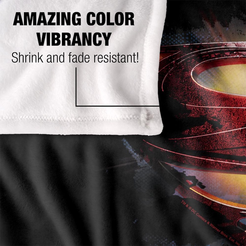 Puede incluir: Una manta blanca con el texto "AMAZING COLOR VIBRANCY" y "Shrink and fade resistant!" impreso. La manta tiene un dise&ntilde;o negro y rojo en el fondo.