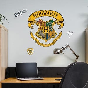 May include: The Hogwarts crest is displayed on a wall, with the words "Hogwarts" in gold lettering. The crest features a shield with four sections, each representing a Hogwarts house. The words "Harry Potter" are also visible.