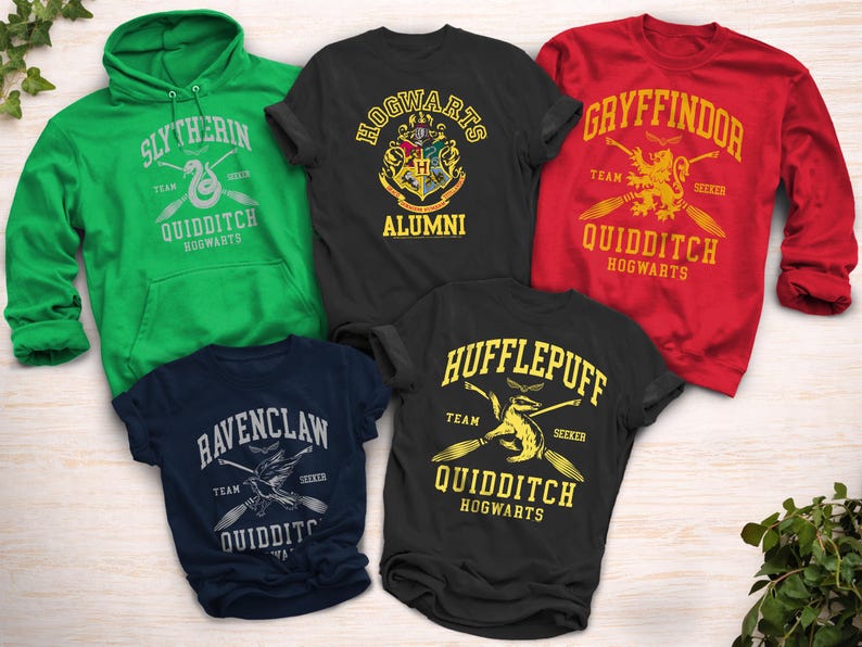 May include: A collection of apparel featuring designs inspired by the Hogwarts houses and Quidditch teams. Includes a green Slytherin hoodie, a black Hogwarts Alumni t-shirt, a red Gryffindor sweatshirt, a navy Ravenclaw t-shirt, and a black Hufflepuff t-shirt.