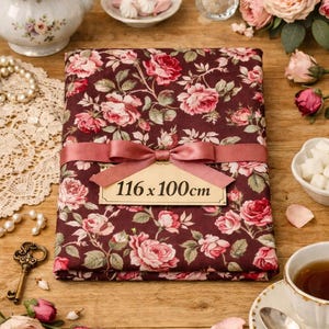 Peut inclure: Un tissu floral bordeaux, mesurant 116 x 100 cm, est noué avec un ruban rose. Le tissu présente un motif de roses roses et de feuilles vertes. L'image comprend une théière, une tasse à thé et des éléments décoratifs.
