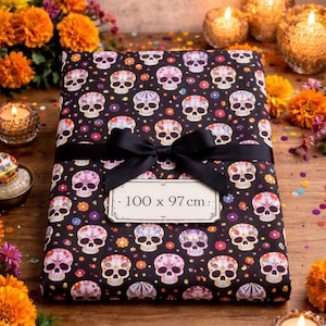 Peut inclure: Un tissu noir orné d'un motif de têtes de mort, noué avec un ruban noir. Le tissu mesure 100 x 97 cm. L'image est décorée de bougies, de fleurs et de confettis colorés, créant une ambiance festive.