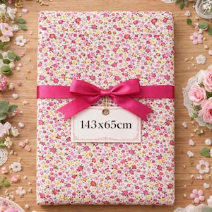 Peut inclure: Un paquet recouvert d'un tissu à motifs floraux, mesurant 143 x 65cm, est noué avec un ruban et un nœud rose vif. Le tissu présente un motif de petites fleurs roses, jaunes et blanches. Le paquet est entouré de fleurs et d'éléments décoratifs.