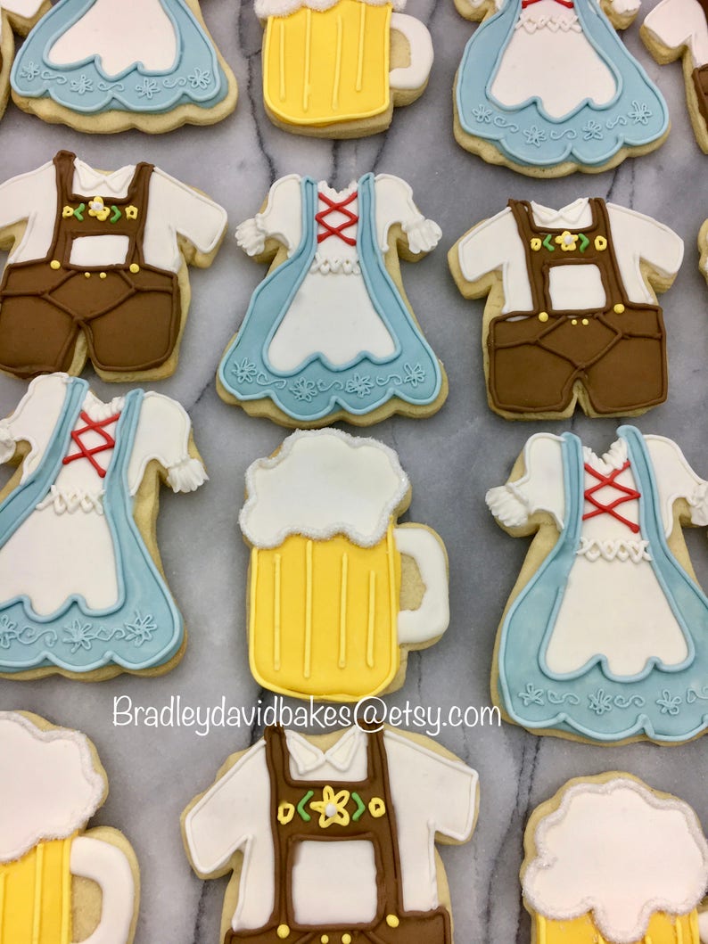 May include: A collection of decorated sugar cookies featuring a variety of designs, including beer steins, dirndls, and lederhosen. The cookies are decorated with white, blue, brown, and yellow icing. The text "Bradleydavidbakes@etsy.com" is visible in the image.