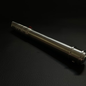 May include: A metallic silver lightsaber prop with a red button, lying on a black surface. The lightsaber has a cylindrical body with a ridged grip section and a detailed emitter.