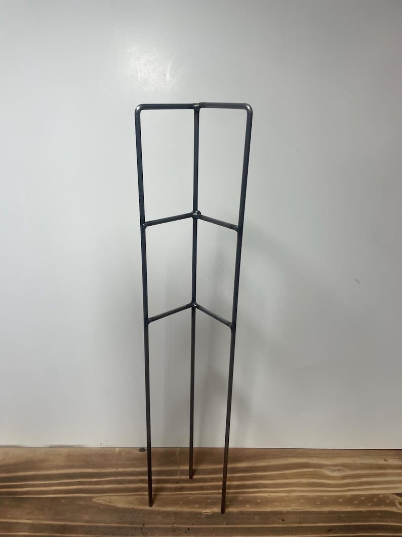 May include: A metal plant stand with three legs and two horizontal bars. The stand is made of black metal and is approximately 30 inches tall.