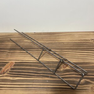 May include: A metal wire rack with three tiers. The rack is made of thin, silver-colored wire and is designed to hold small items.