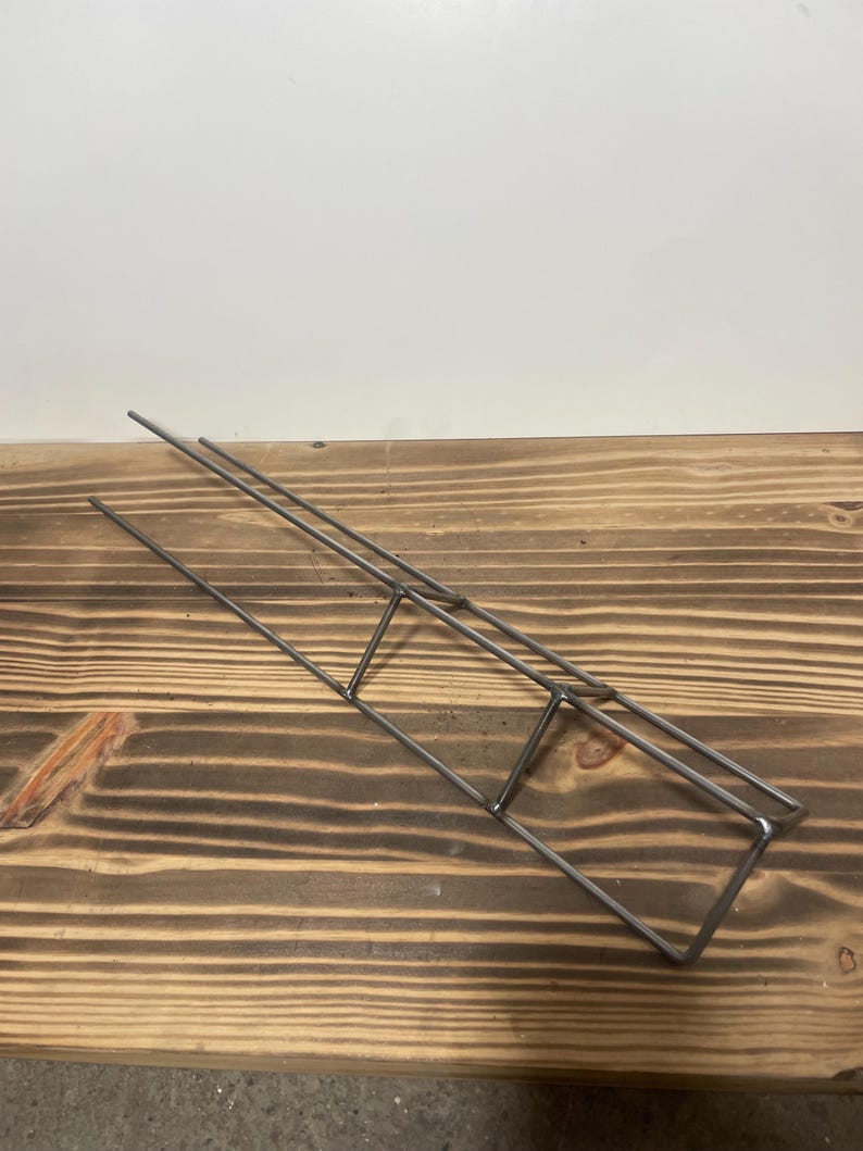 May include: A metal wire rack with three tiers. The rack is made of thin, silver-colored wire and is designed to hold small items.