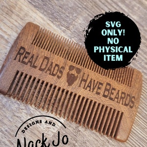 May include: A wooden comb with the text "REAL DADS HAVE BEARDS" engraved on it. The comb is brown and has a rounded shape. The text "DESIGNS AND Nack Jo HOMEMADE TREATS" is also engraved on the comb.