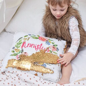 May include: A white pillow with gold sequins and floral embroidery. The pillow has the name "Annistyn" written in pink lettering. A young girl is sitting in a white tent holding the pillow.