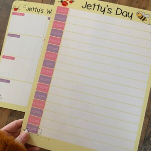 K&ouml;nnte beinhalten: Ein gelbes Trockenl&ouml;schboard mit einem Bienen- und Marienk&auml;fer-Design. Das Board hat einen Titel, der "Jetty's Day" lautet, und eine Spalte f&uuml;r jede Stunde des Tages von 6:00 Uhr morgens bis 21:00 Uhr abends.