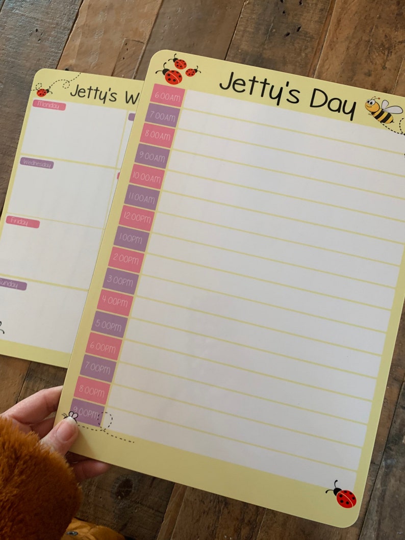 K&ouml;nnte beinhalten: Ein gelbes Trockenl&ouml;schboard mit einem Bienen- und Marienk&auml;fer-Design. Das Board hat einen Titel, der "Jetty's Day" lautet, und eine Spalte f&uuml;r jede Stunde des Tages von 6:00 Uhr morgens bis 21:00 Uhr abends.