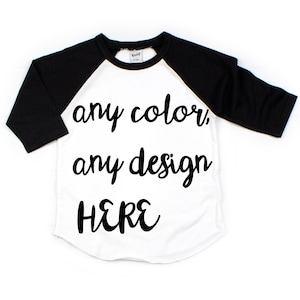 Puede incluir: Una camiseta de béisbol blanca y negra con el texto "any color, any design HERE" impreso en la parte delantera.