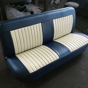 以下が含まれることがあります： ツートンカラーの車のベンチシート。シートは、ネイビーブルーのビニール外装と、クリーム色の垂直リブインサートが特徴です。シートは、カーブした背面と丸みを帯びたベースで設計されており、クラシックまたはヴィンテージスタイルを示唆しています。