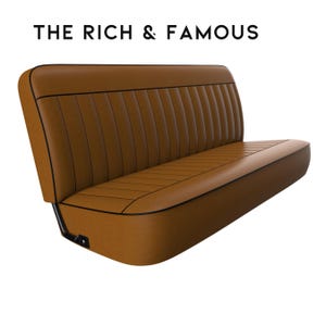 May include: A brown leather bench seat with black piping. The seat has a tufted design and is made for a vehicle.