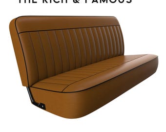 May include: A brown leather bench seat with black piping. The seat has a tufted design and is made for a vehicle.