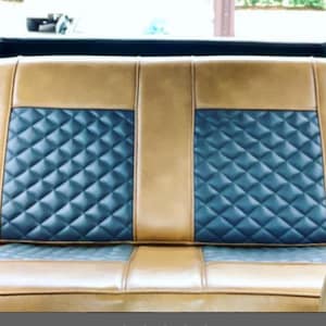 May include: A tan and navy blue quilted car seat back. The seat back has a diamond pattern in the center and tan leather on the sides. The seat is in a vehicle.
