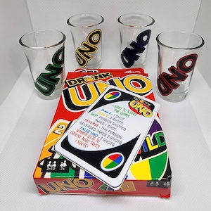May include: A "DRINK UNO" game set featuring a red box and four clear shot glasses, each with a different coloured "UNO" logo. A game card displays the rules. The game is designed for 2-10 players.