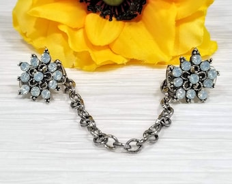 May include: A silver chain with two decorative snowflake-shaped charms. Each charm is adorned with clear, iridescent rhinestones.