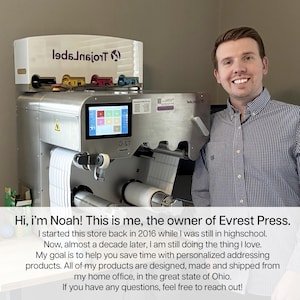 Smiling small business owner standing beside a commercial label printer with rolls of labels. Text overlay introduces him as Noah, founder of Everest Press, highlighting his personalized products and home-based business in Ohio.