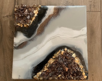 May include: Square abstract art painting with white, black, and gold glitter. The painting features two large areas of black with gold glitter, and a white background with black and gold glitter swirls.