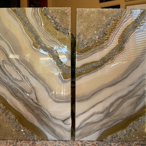 Puede incluir: Dos piezas de arte abstracto con un esquema de color blanco, gris y dorado. Las piezas presentan un dise&ntilde;o de remolino, fluido con brillo y cristales incrustados.
