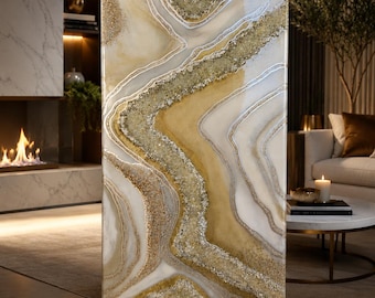 May include: Abstract art piece with a layered design. The artwork features a blend of white, gold, and silver tones, with textured elements. The piece is rectangular and stands upright, showcasing a modern aesthetic. The artist's signature "Faiza Studio.art" is visible.