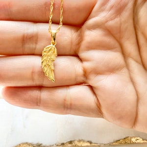 K&ouml;nnte beinhalten: Eine goldene Kettenkette mit einem zarten goldenen Engelsfl&uuml;gel-Anh&auml;nger.