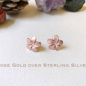 Puede incluir: Un par de pendientes de flor de plumeria en oro rosa sobre plata de ley.