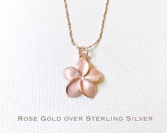 May include: A rose gold over sterling silver necklace with a delicate plumeria flower pendant.