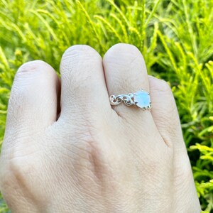 May include: A silver ring featuring a white gemstone set in a delicate floral design.
