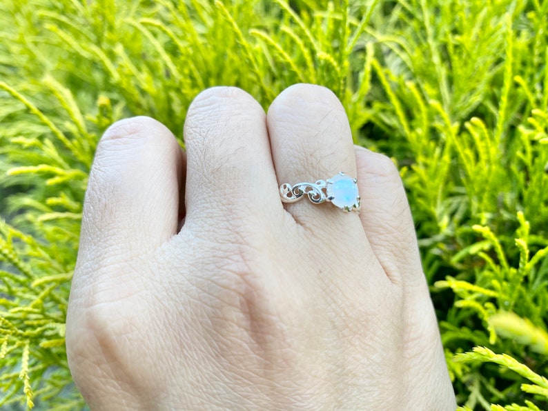 May include: A silver ring featuring a white gemstone set in a delicate floral design.