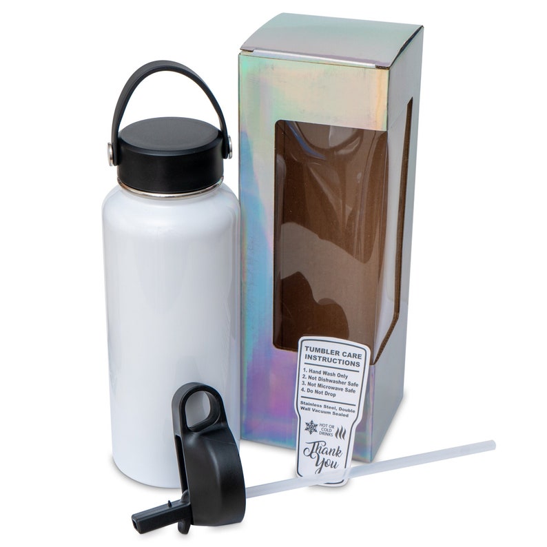 May include: A white stainless steel tumbler with a black lid and handle, next to its iridescent box. The tumbler has a straw and a separate black lid. A sticker on the box reads "Thank You" and "Tumbler Care Instructions."