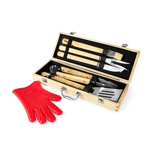 May include: A barbecue tool set in a light wooden box, featuring stainless steel utensils with wooden handles. The set includes a spatula, tongs, fork, brush, and knife. A red silicone oven mitt is placed beside the box.