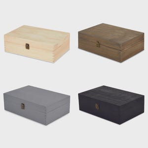May include: Four rectangular wooden boxes with hinged lids and metal clasps. The boxes are in different colors: natural wood, brown, gray, and black. The boxes are likely for storage or display.