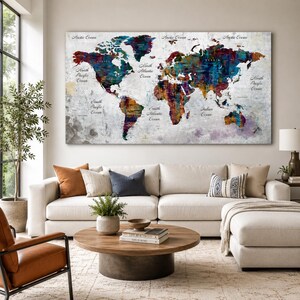 May include: A large rectangular wall art piece featuring a world map with a distressed, textured background. The continents are rendered in vibrant, abstract splashes of blue, red, yellow, and purple paint. Ocean names are printed in black text.