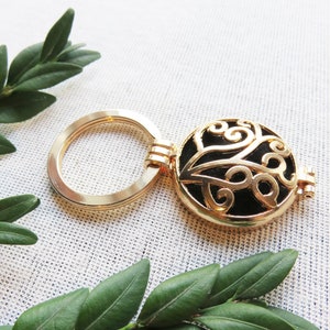 Peut inclure: Porte-clés doré avec un charme rond en filigrane noir et or. Le charme a un design délicat et complexe.