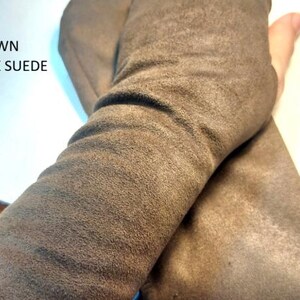 May include: A pair of brown faux suede fingerless gloves with a soft, matte texture. The fabric is flexible and covers the forearm, featuring a thumb opening. The text BROWN FAUX SUEDE is printed in black on the upper left side of the image.
