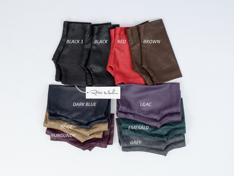 May include: A collection of fingerless gloves in various colors including black, red, brown, dark blue, lilac, beige, burgundy, emerald, and grey. Each pair features a textured finish and a thumb opening. A white tag with the text Rita Marlin is visible.