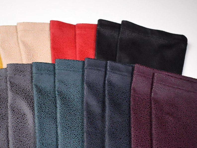 May include: A collection of rectangular fabric pouches featuring a textured, crackled surface pattern. The pouches are arranged in a fan-like display and come in various colors including beige, red, black, dark gray, teal, navy, and deep purple.