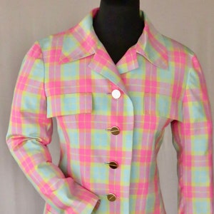 Op de afbeelding: Een lichtblauwe blazer met een roze en gele ruitpatroon. De blazer heeft een kraag, lange mouwen en vijf gouden knopen aan de voorkant.